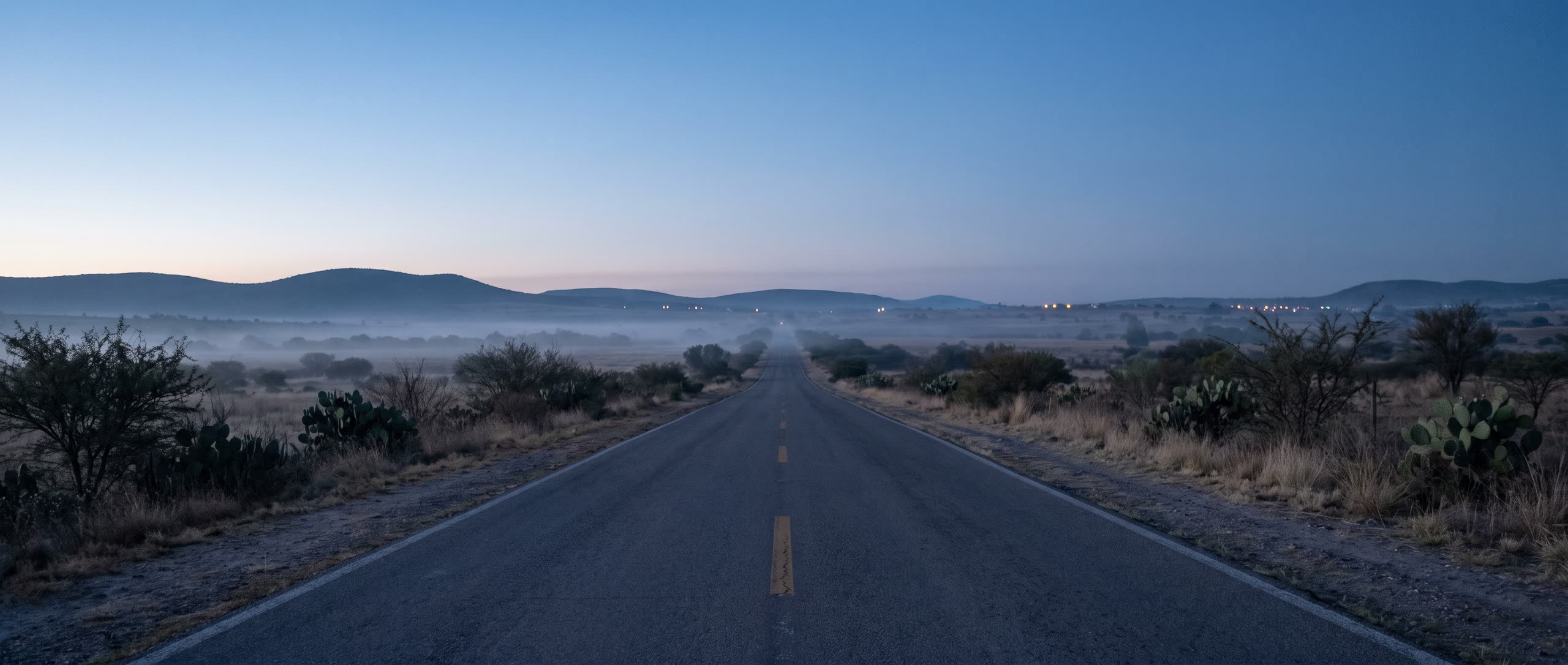 An empty road at dawn between hills