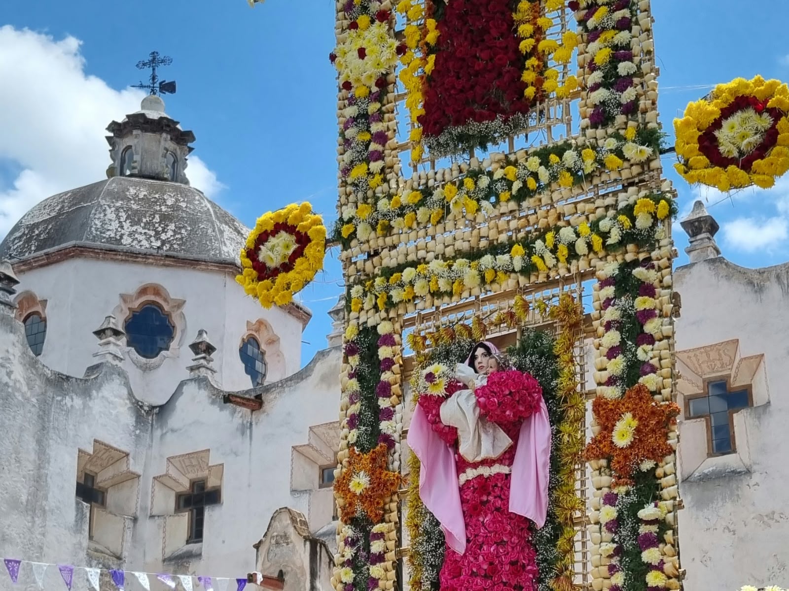 A doorway covered in yellow and red flowers beside a white dome